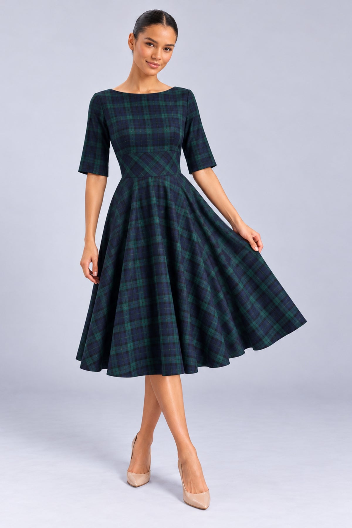 Model wearing the Hepburn Forest and Navy Plaid Swing Dress, showing the bateau neckline, fitted waist and full circle skirt.