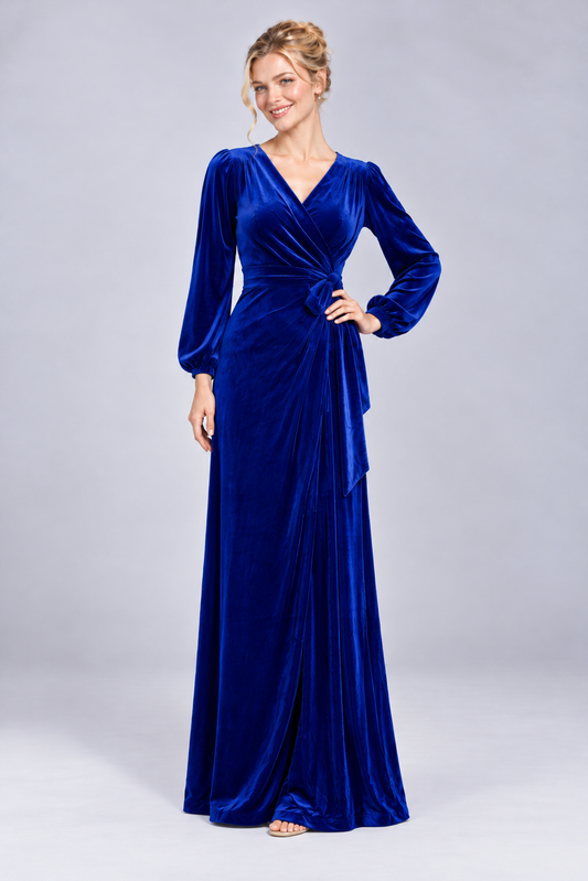 Model wearing Angelique sapphire blue velvet wrap evening gown with gathered long sleeves and adjustable tie waist.